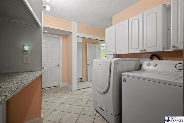 washroom with light tile patterned floors, washer and dryer, and a textured ceiling