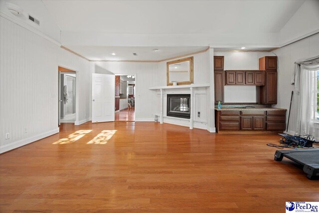 unfurnished living room with crown molding and light wood-type flooring