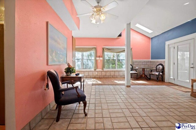 interior space with ceiling fan and lofted ceiling with skylight