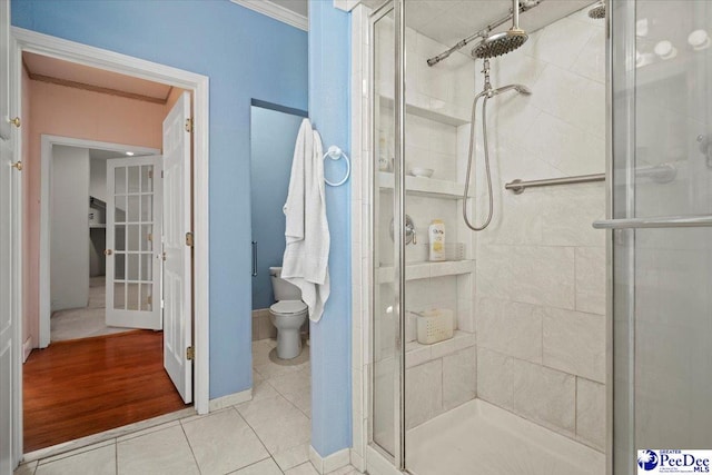 bathroom with crown molding, tile patterned floors, toilet, and a shower with door