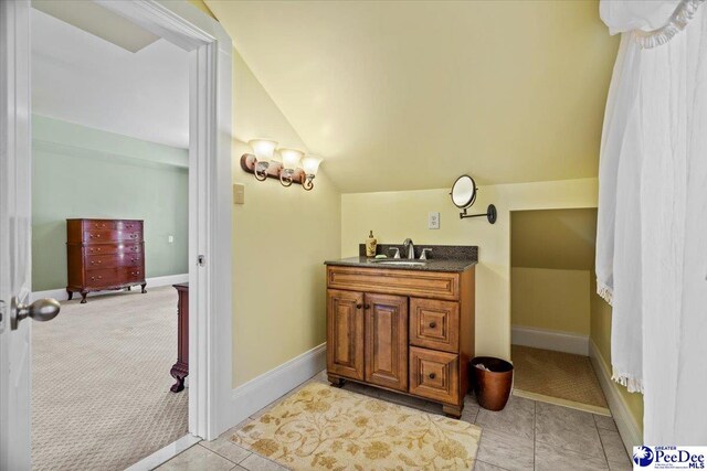 bathroom with vanity, vaulted ceiling, and tile patterned floors