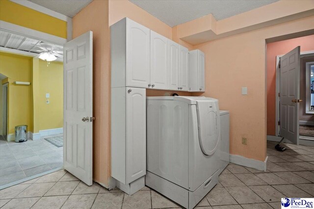 laundry area with light tile patterned floors, a textured ceiling, cabinets, and washing machine and clothes dryer