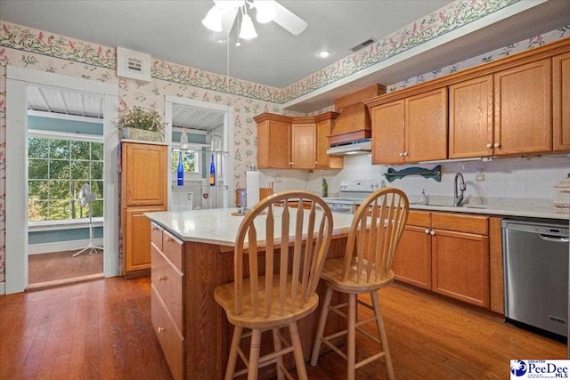 kitchen with a breakfast bar, sink, wood-type flooring, a center island, and stainless steel dishwasher