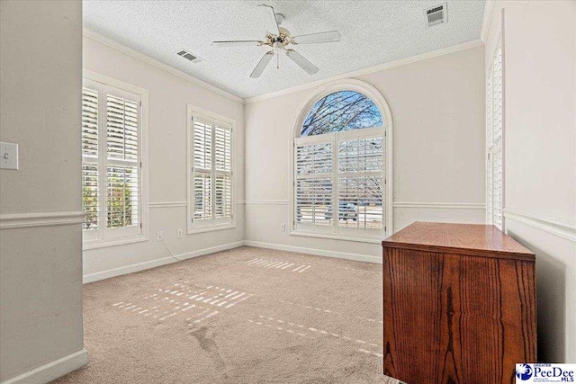 empty room featuring visible vents, a textured ceiling, and ornamental molding