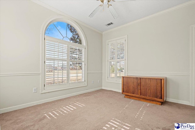 spare room featuring carpet, visible vents, baseboards, and ornamental molding