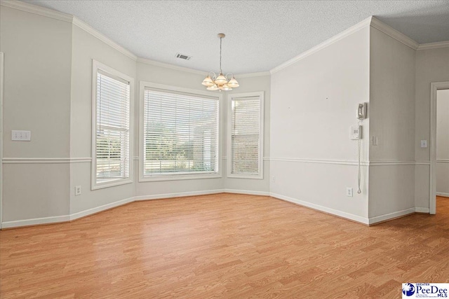 unfurnished dining area featuring light wood-style floors, visible vents, ornamental molding, and an inviting chandelier