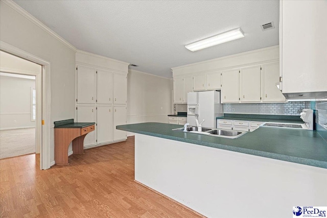 kitchen with white fridge with ice dispenser, stove, dark countertops, and white cabinets