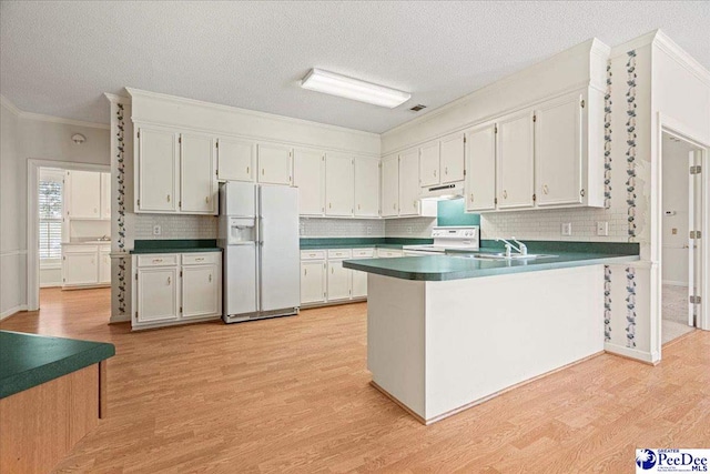 kitchen featuring dark countertops, stove, white cabinets, white fridge with ice dispenser, and a peninsula