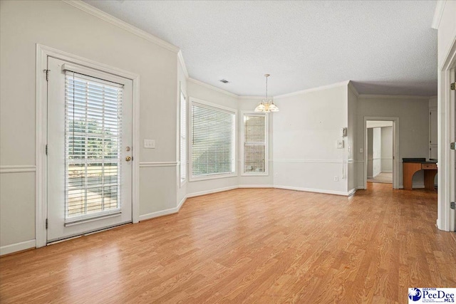 unfurnished dining area with ornamental molding, baseboards, light wood-style flooring, and a textured ceiling