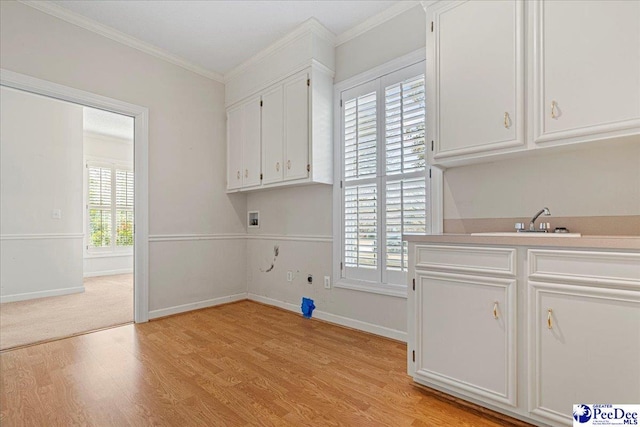 clothes washing area with a wealth of natural light, cabinet space, crown molding, and light wood finished floors