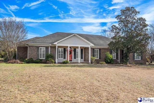 view of front of home with a porch, a front lawn, and brick siding