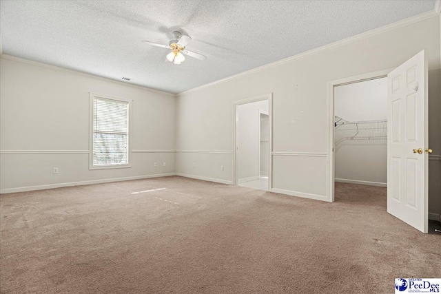 unfurnished bedroom featuring light carpet, a spacious closet, ornamental molding, and a textured ceiling