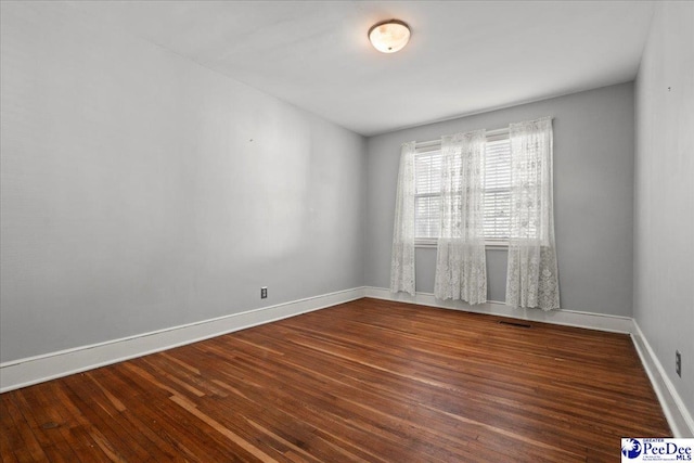 spare room featuring visible vents, baseboards, and wood finished floors