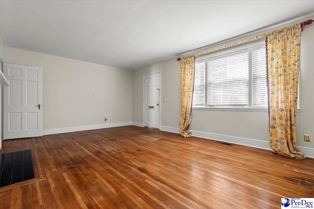 unfurnished living room featuring visible vents, hardwood / wood-style flooring, and baseboards