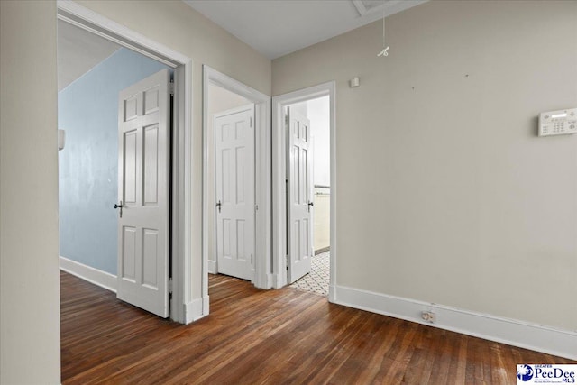 hall featuring attic access, baseboards, and wood finished floors