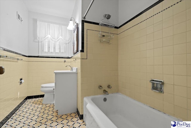 bathroom featuring tile walls, shower / washtub combination, visible vents, and toilet