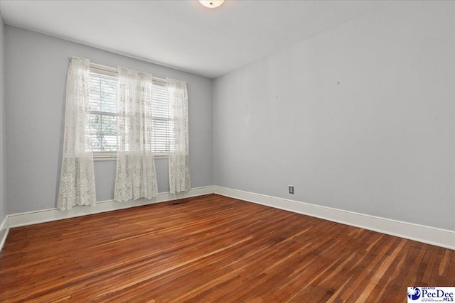 empty room featuring wood finished floors and baseboards