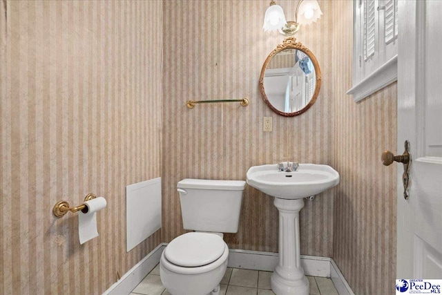 half bathroom with wallpapered walls, baseboards, tile patterned flooring, and toilet