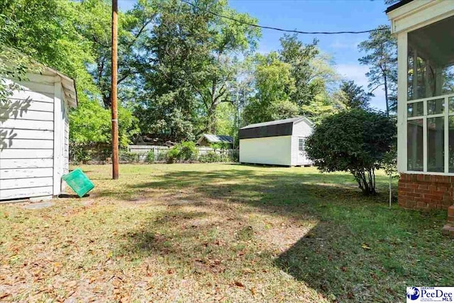 view of yard featuring fence, an outdoor structure, and a shed