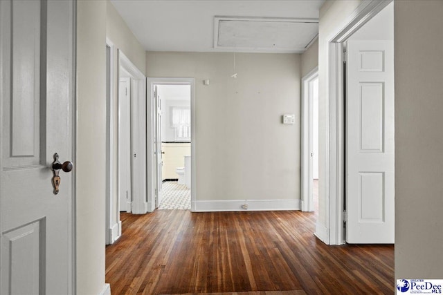 hall featuring attic access, baseboards, and dark wood-style floors