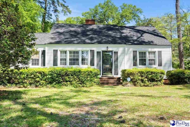 view of front of house featuring a chimney, roof with shingles, and a front yard
