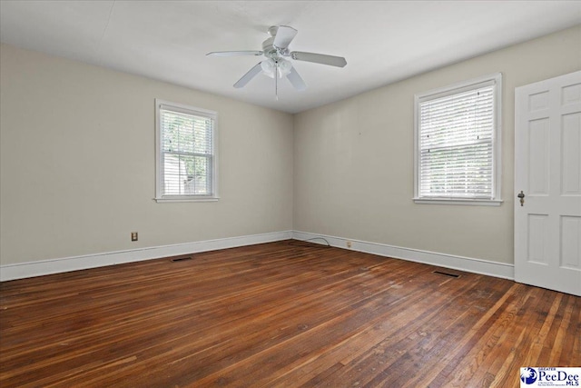 spare room with wood finished floors, visible vents, a ceiling fan, and baseboards