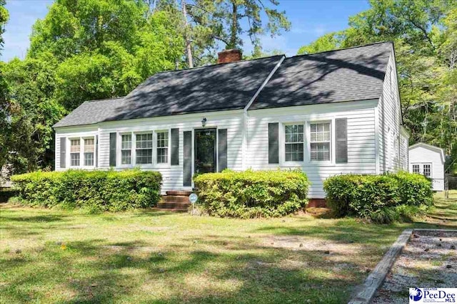 view of front of property featuring entry steps, roof with shingles, a chimney, and a front lawn