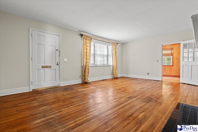 unfurnished living room with plenty of natural light, baseboards, and wood finished floors