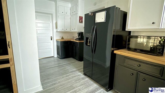 kitchen featuring white cabinetry, butcher block counters, light wood-type flooring, and black appliances