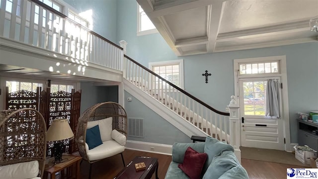 interior space featuring coffered ceiling, hardwood / wood-style floors, a towering ceiling, and beamed ceiling