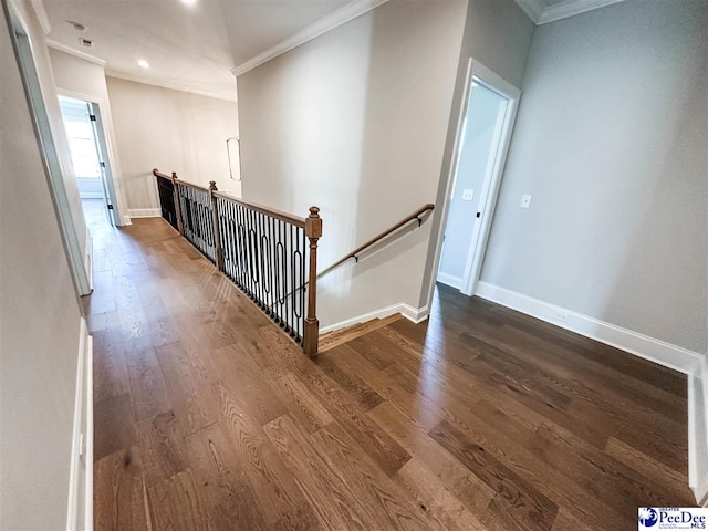 hallway featuring baseboards, wood finished floors, an upstairs landing, and crown molding