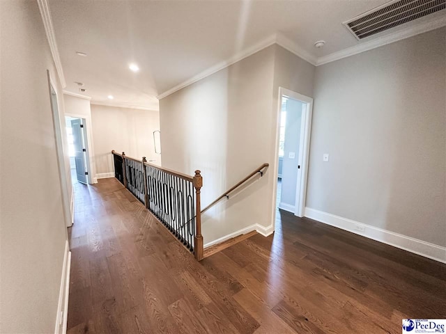 hallway featuring ornamental molding, visible vents, dark wood finished floors, and an upstairs landing