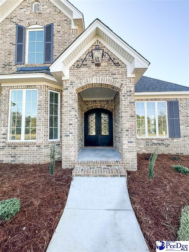 entrance to property featuring french doors and brick siding