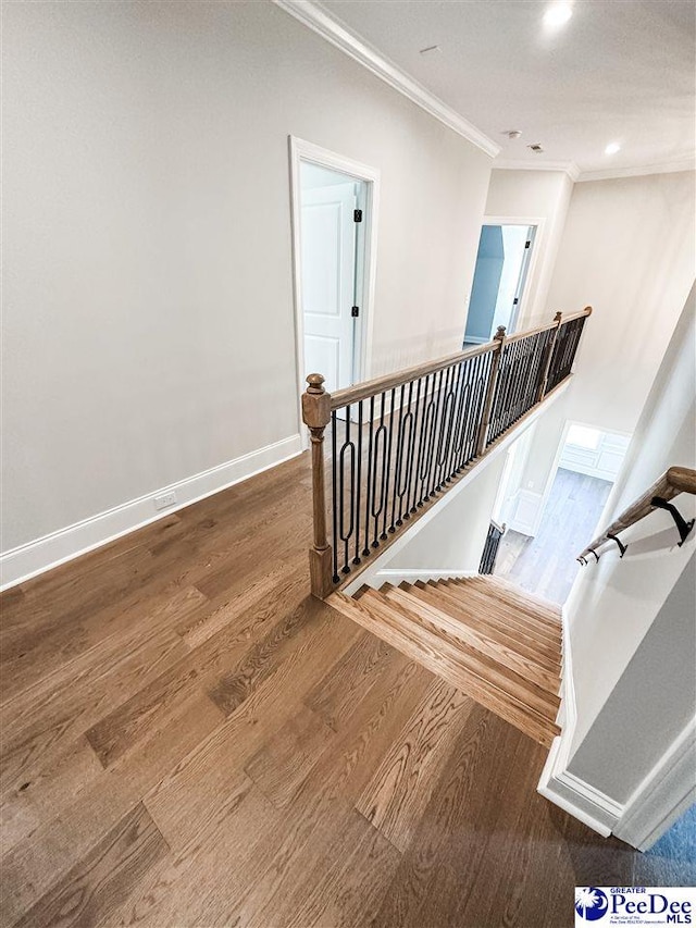 staircase featuring crown molding, baseboards, wood finished floors, and recessed lighting