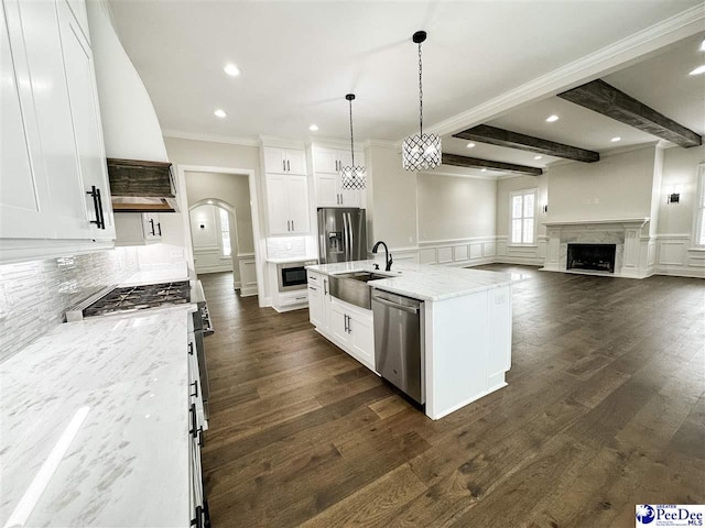 kitchen featuring stainless steel appliances, a kitchen island with sink, white cabinets, and light stone counters