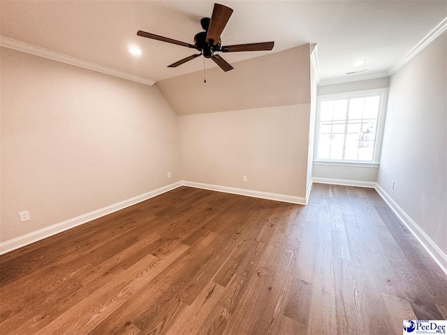 empty room with lofted ceiling, wood finished floors, a ceiling fan, baseboards, and ornamental molding