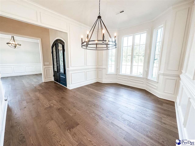 unfurnished dining area featuring a chandelier, arched walkways, visible vents, and a decorative wall