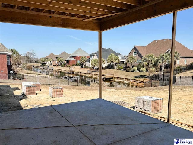 view of patio / terrace featuring a water view, a residential view, and fence