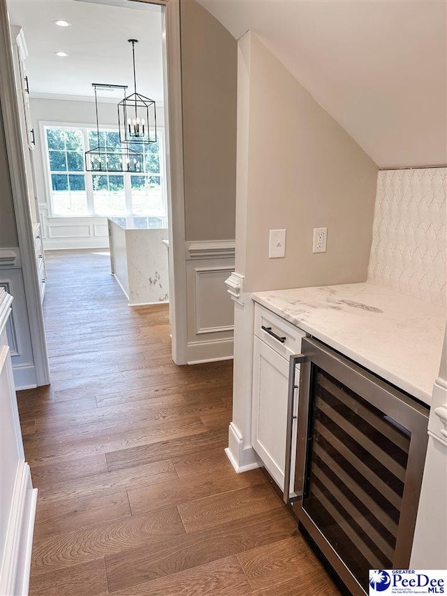 kitchen featuring wine cooler, light stone counters, dark wood-style flooring, white cabinetry, and pendant lighting