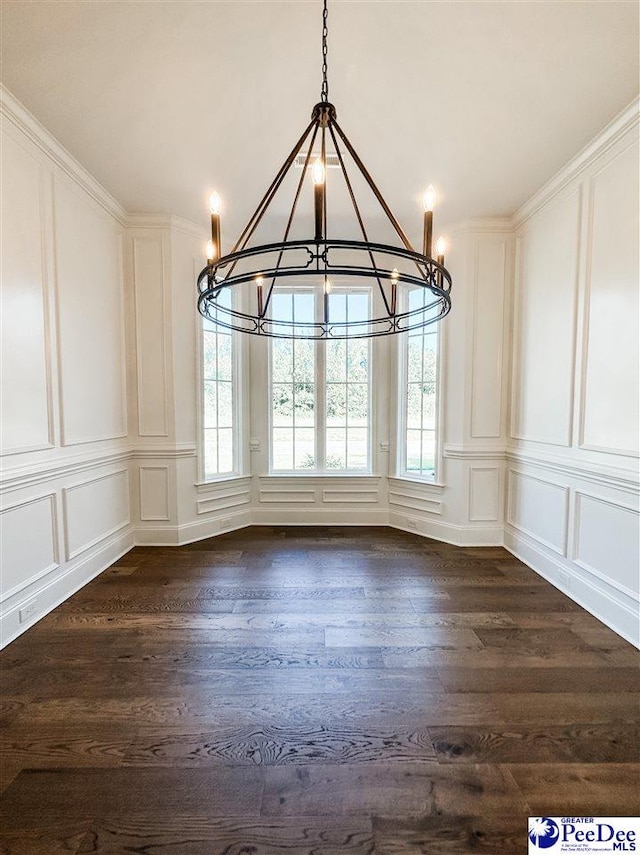 unfurnished dining area featuring dark wood-style flooring, a chandelier, a decorative wall, and a wealth of natural light