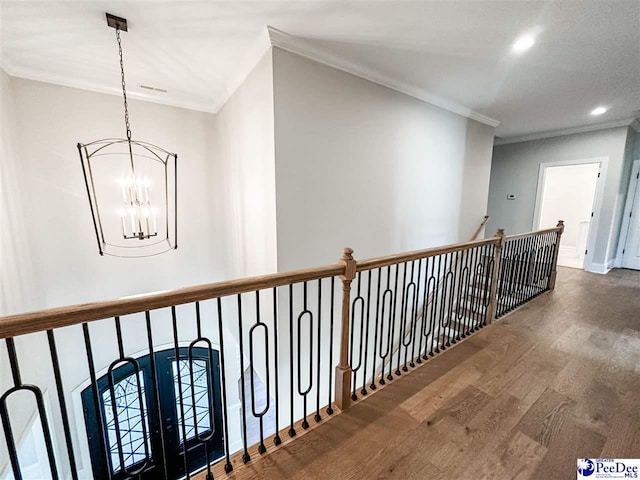 corridor with a notable chandelier, recessed lighting, wood finished floors, and crown molding