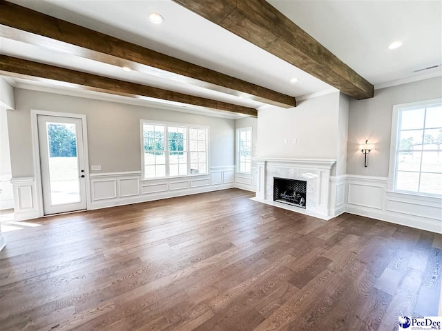 unfurnished living room with dark wood-style floors, beam ceiling, a fireplace, and plenty of natural light