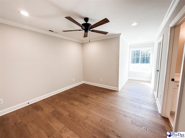 spare room featuring ornamental molding, visible vents, baseboards, and wood finished floors