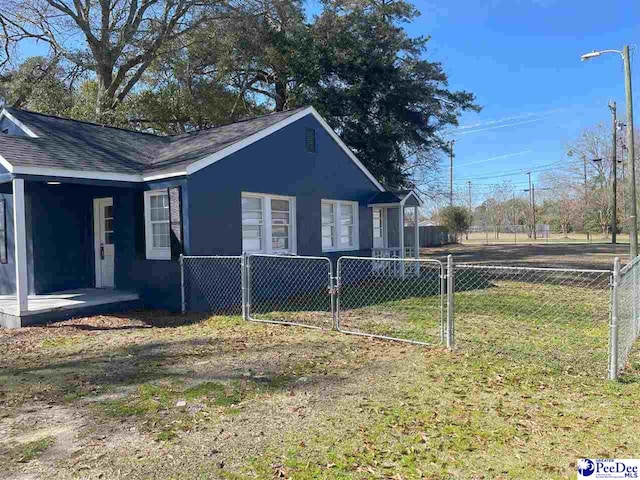 view of side of home featuring a fenced front yard and a lawn