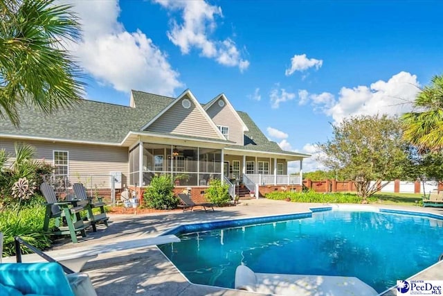 view of swimming pool with a sunroom, a diving board, and a patio area