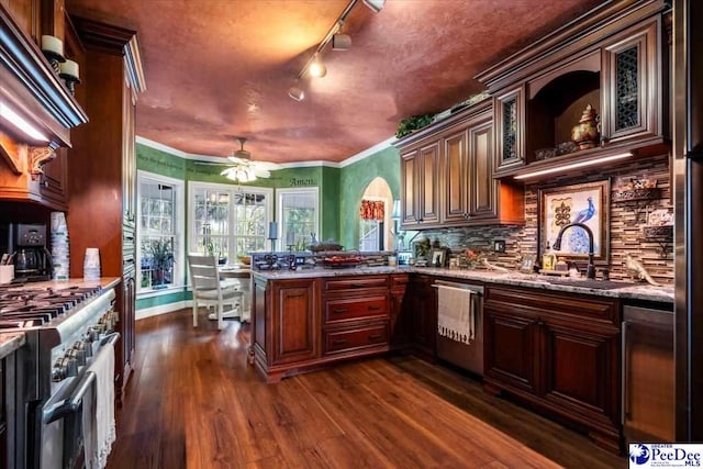 kitchen with sink, light stone counters, dark hardwood / wood-style flooring, kitchen peninsula, and stainless steel appliances