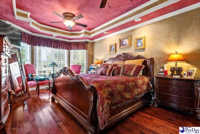 bedroom with ornamental molding, dark hardwood / wood-style floors, ceiling fan, and a tray ceiling