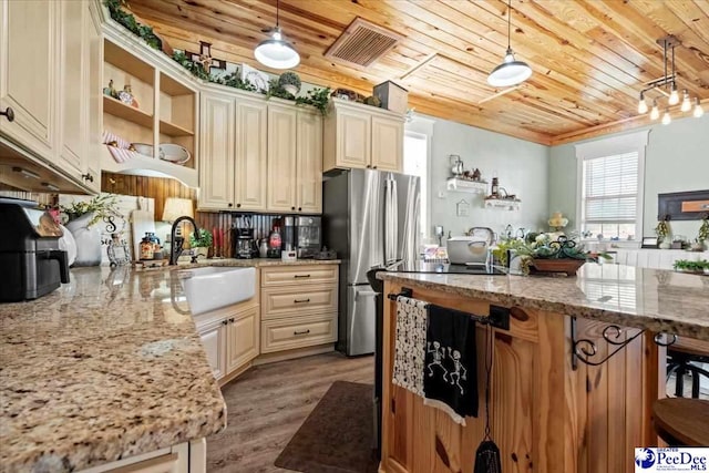 kitchen featuring light stone counters, sink, and decorative light fixtures