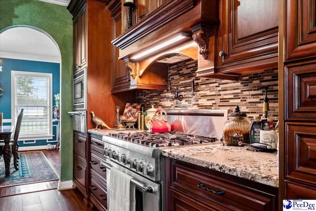 kitchen with premium range hood, tasteful backsplash, ornamental molding, stainless steel appliances, and light stone countertops