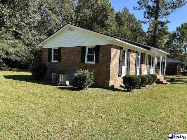 view of side of home with a yard and central AC unit